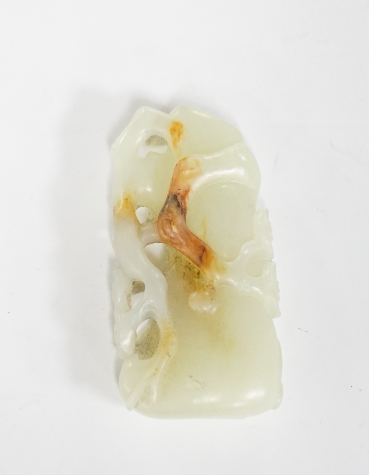 A Chinese pale celadon and russet jade carving of a prunus bough, 5.4cm